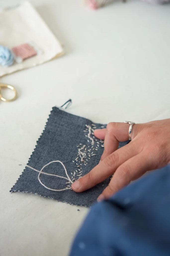 Mano rematando muestra de bordado colores delicados