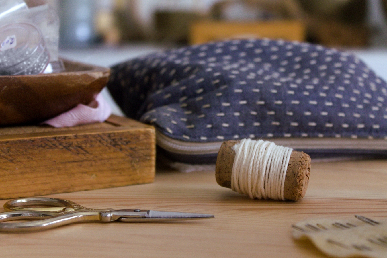 materiales de bordado sobre mesa de madera, carrete de hilo, agujas y tijera