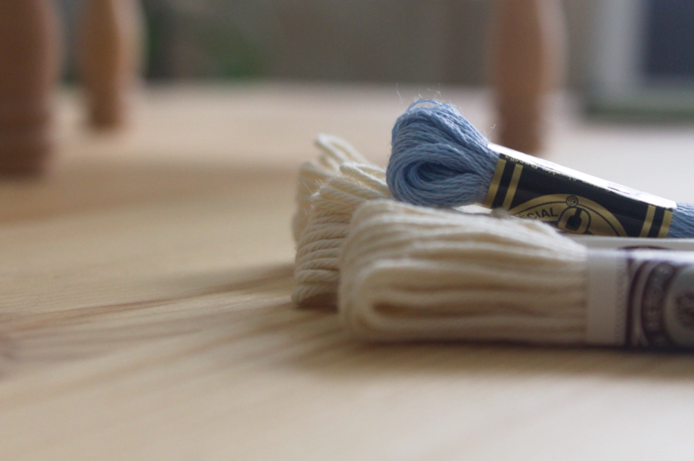hilos de bordado blanco y celeste sobre mesa de madera